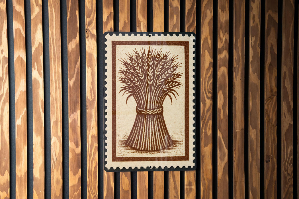 a wooden wall with a framed illustration of a wheat stalk, which appears to be a decorative piece or a sign.
