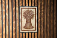 a wooden wall with a framed illustration of a wheat stalk, which appears to be a decorative piece or a sign.