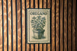 A vintage-style sign with the word "OREGANO" printed on it, featuring an illustration of a potted plant.
