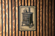 a vintage-style stove with a teapot on top, displayed on a wooden wall.