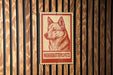 A red and white sign with a dog's head on it, mounted on a wooden wall.