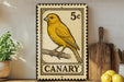 a canary, a yellow bird, perched on a branch. The canary is depicted in a postage stamp-like design, with the word "CANARY" written below it. The canary is also shown in a 5c stamp, indicating its value. The canary is surrounded by various kitchen items, such as a cutting board, a knife, and a bowl, suggesting a kitchen setting.