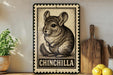 A framed illustration of a chinchilla is displayed on a shelf, accompanied by a wooden cutting board, a potted plant, and some lemons.