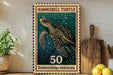 A framed stamp-like artwork depicting a hawksbill turtle, with the text "HAWKSBILL TURTLE" and "50 Erotmochely'simbricata" printed on it. The artwork is displayed on a shelf next to a wooden cutting board and some potted plants.