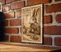 A wooden sign with a rabbit sitting at a table, holding a teapot and cup, against a brick wall background.