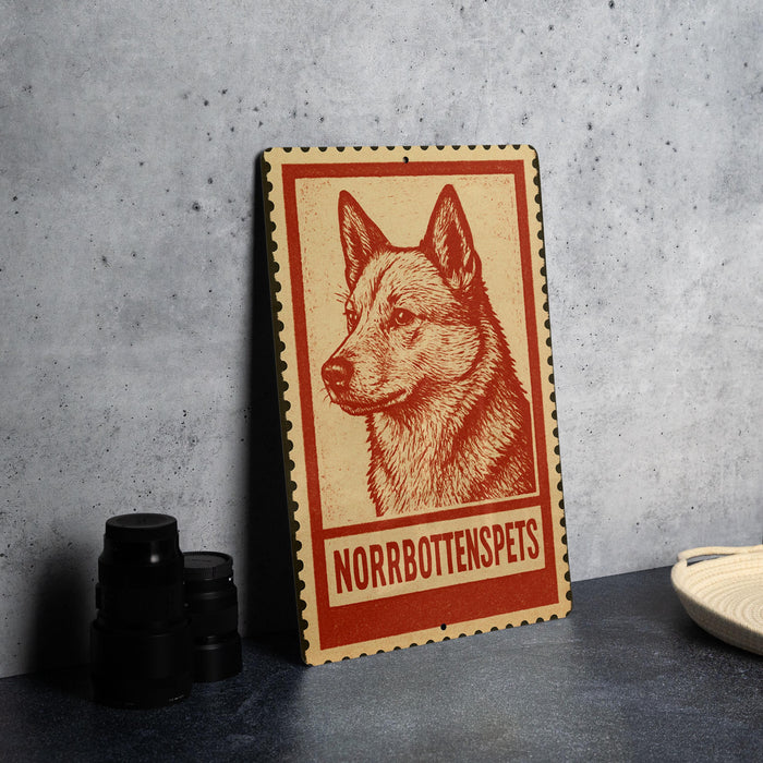 A wooden sign with a red border and a red and white illustration of a dog's head, along with the text "NORROBOTTENSPETS" on the sign.