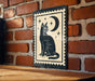 A black cat sitting on a brick wall, with a crescent moon and stars above it, is depicted in the image.