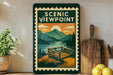 a framed poster of a scenic viewpoint with mountains, trees, and a bench, displayed on a shelf next to a wooden cutting board and a potted plant.