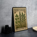 A metal sign with a vintage-style illustration of herbs and spices, including parsley, rosemary, and thyme, is displayed on a table.