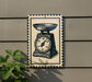 A vintage-style metal sign with a black and white illustration of a scale on it, mounted on a wall.