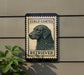 a sign with a curly-coated retriever dog on it, mounted on a wall next to a plant.