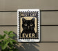 A sign with a black cat illustration and the text "BEST CAT EVER" is displayed on a wall, with a plant visible to the left.