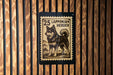 A 25 Lapponian Herder dog is depicted on a wooden wall, with a black and white postage stamp-like design above it.