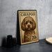 a small, detailed illustration of a dog on a postage stamp, placed on a table next to some black camera lenses.