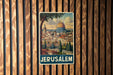 A vintage-style poster of Jerusalem, featuring the iconic Dome of the Rock, is displayed on a wooden wall.