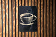 A black and white illustration of a cup of coffee is displayed on a wooden wall.