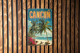 A vintage-style metal sign with the word "CANCUN" prominently displayed, featuring palm trees and a beach scene.