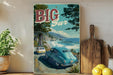 A vintage-style metal sign with a colorful illustration of a car driving on a road near a beach, with palm trees and mountains in the background.
