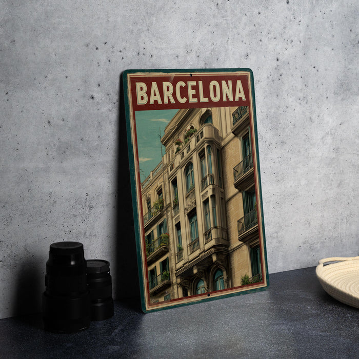 A framed poster of a building in Barcelona, Spain, is displayed on a table next to some black camera lenses.