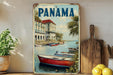 A vintage-style metal sign with a painting of boats on a river, surrounded by palm trees and buildings, is displayed on a shelf next to a wooden cutting board and some potted plants.