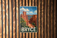 A vintage-style poster of Bryce Canyon National Park, featuring the iconic red rock formations and a blue sky with clouds.