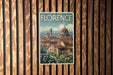 A vintage-style poster of Florence, Italy, featuring the iconic dome of the Florence Cathedral and the city's historic architecture, is displayed on a wooden wall.