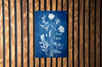a blue sign with white floral designs on it, mounted on a wooden wall.