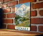 A vintage-style metal sign with a mountain landscape and a river, mounted on a brick wall.
