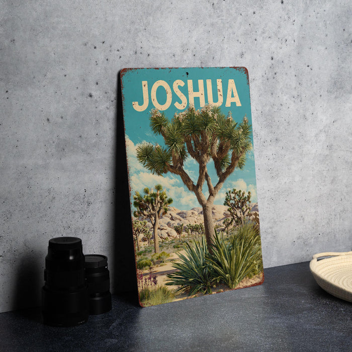 A vintage-style metal sign with the word "JOSUA" prominently displayed, featuring a desert landscape with a palm tree and other desert plants.