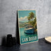 A framed vintage-style poster of a boat on a tropical beach, with palm trees and a blue sky in the background, is displayed on a wall.