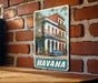 A vintage-style metal sign featuring a colorful illustration of a building and a car, with the word "HAVANA" prominently displayed.