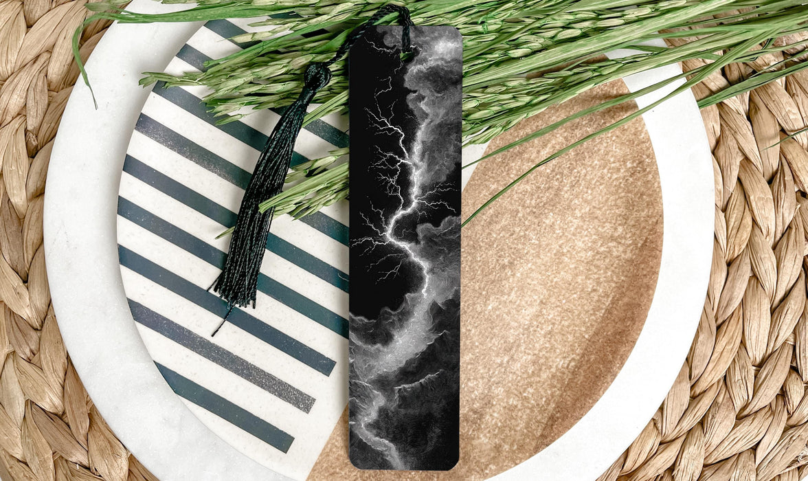 A black and white bookmark with a lightning bolt design is placed on a plate with a striped pattern, surrounded by green grass.