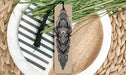 A decorative bookmark with a detailed illustration of a bull's head is placed on a plate with a striped pattern.