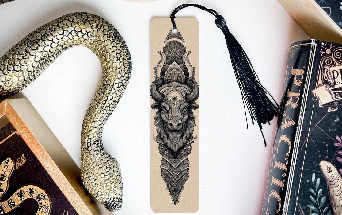 a snake-like object, a bookmark with an intricate design, and a book, all arranged on a white surface.