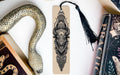 a snake-like object, a bookmark with an intricate design, and a book, all arranged on a white surface.