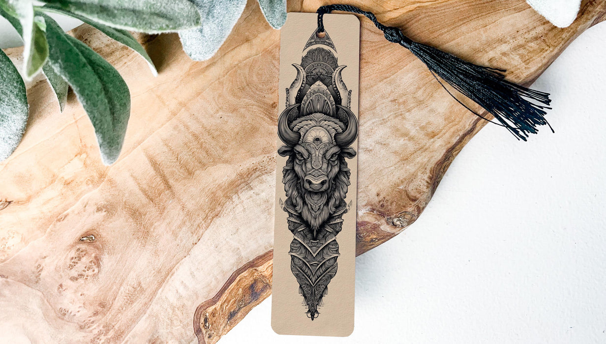 A wooden surface with a decorative bookmark featuring an intricate black and white illustration of a bull's head.