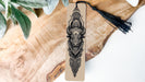 A wooden surface with a decorative bookmark featuring an intricate black and white illustration of a bull's head.