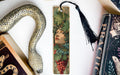 a decorative bookmark with a snake design and a woman's face on it, placed on a white surface next to a book.