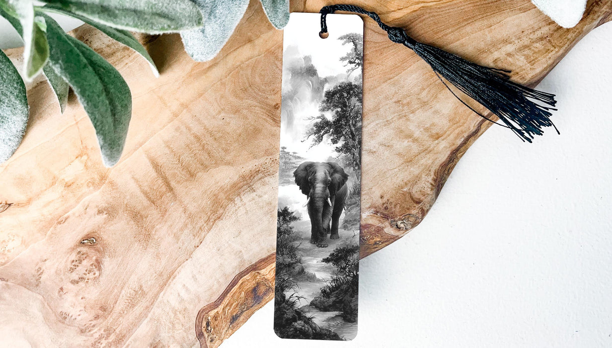 A black and white photograph of an elephant walking through a forest, displayed on a wooden surface with a black tassel hanging from the top.