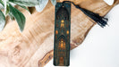 A wooden bookmark with an intricate design of a cathedral or church, featuring stained glass windows and a tassel.