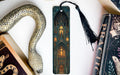 a decorative snake-shaped bookmark with an ornate design, placed next to a book titled "Practice" and a black tassel.