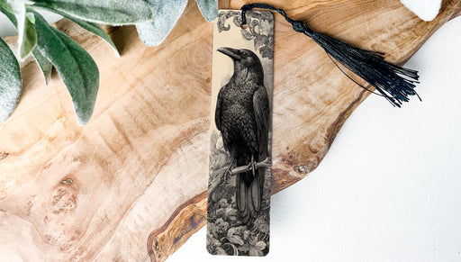 A wooden surface with a black and white illustration of a bird perched on a branch, accompanied by a black tassel.