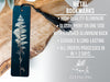 a metal bookmark with a black tassel, placed on a wooden surface.