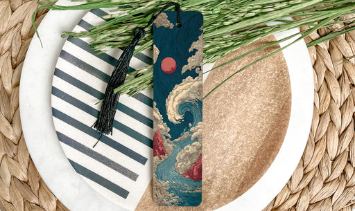 A decorative bookmark with a wave design and a tassel is placed on a plate with a striped pattern and a pile of green grass.