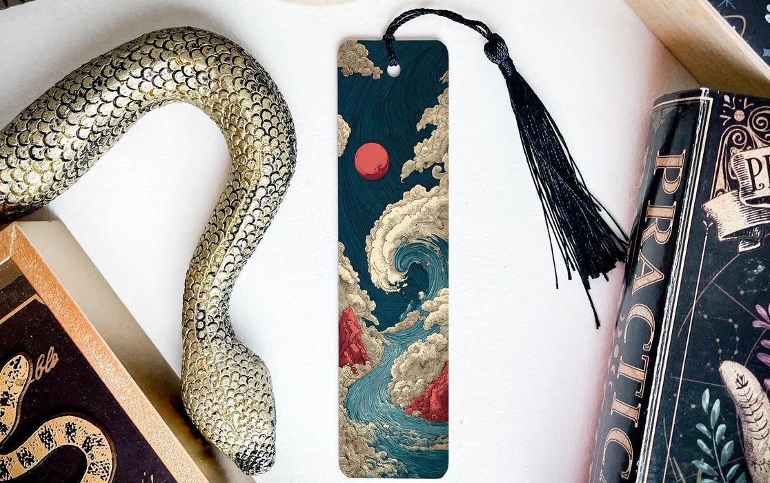 a snake-shaped bookmark with a colorful, abstract design, placed next to a book and a black tassel.