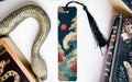 a snake-shaped bookmark with a colorful, abstract design, placed next to a book and a black tassel.