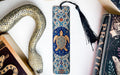 A decorative snake-shaped bookmark with a blue and gold design, a black tassel, and a book titled "PRACTICAL" are displayed on a white surface.