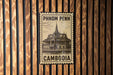 A metal sign with text and an illustration of a building, mounted on a wooden wall.