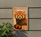 A red panda stamp is affixed to a gray wall, featuring a close-up of the panda's face.