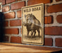 a sign with a picture of a wild boar on it, mounted on a brick wall.